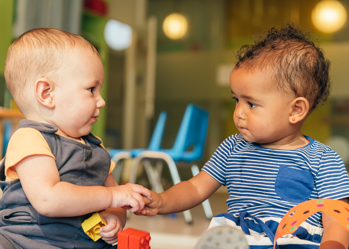 Babies playing together, holing hands in a daycare setting